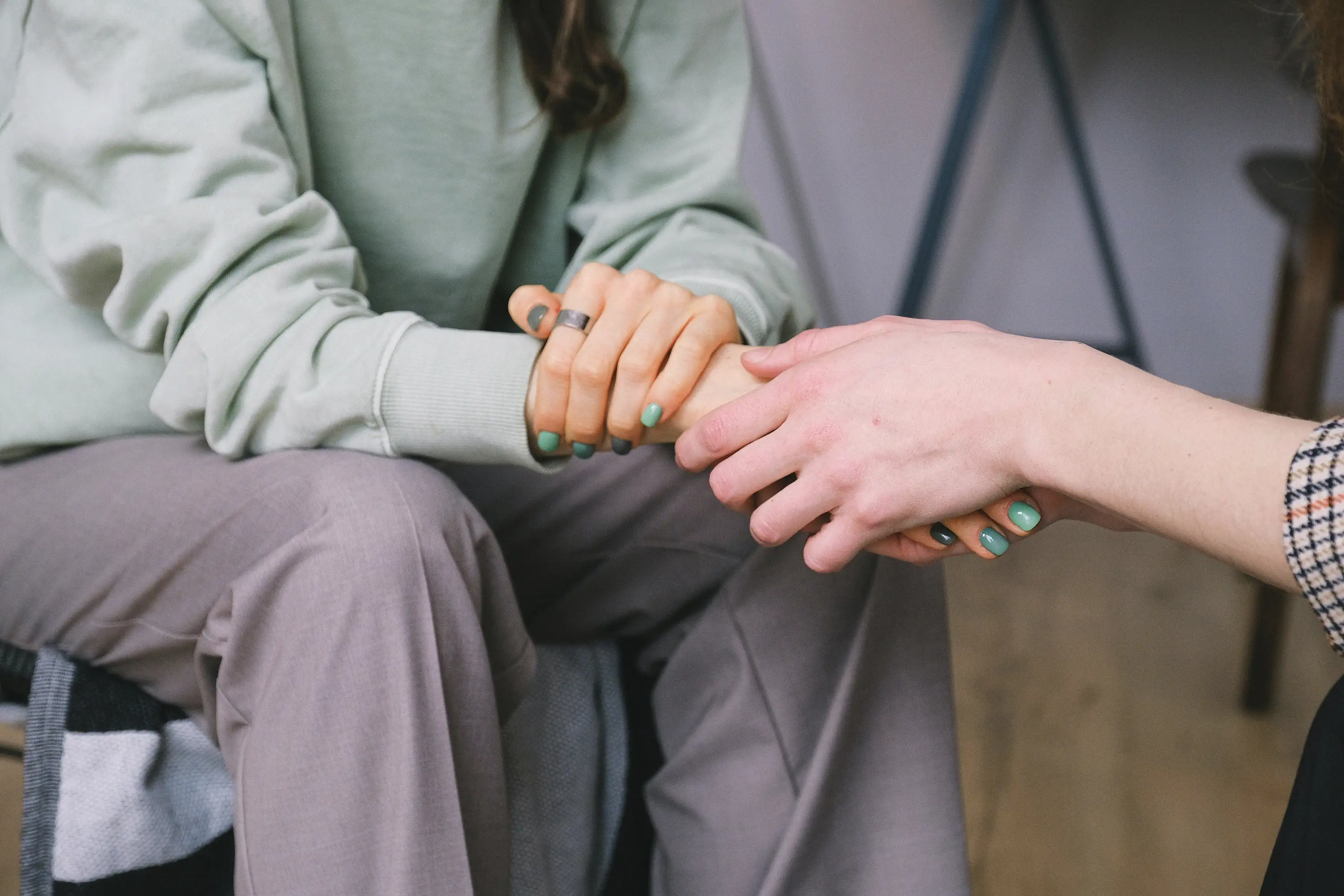 two people sitting down holding each other's hands